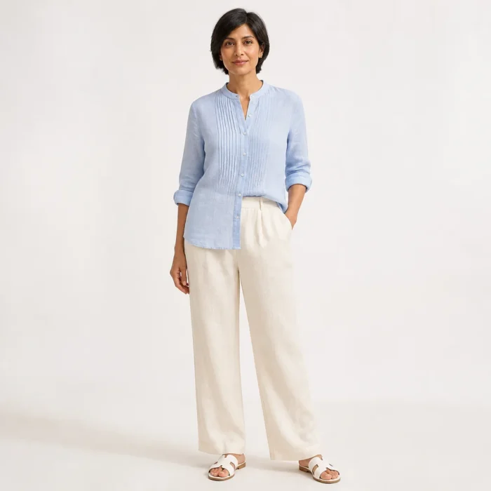 Woman in a powder blue pintucked linen shirt and ecru trousers